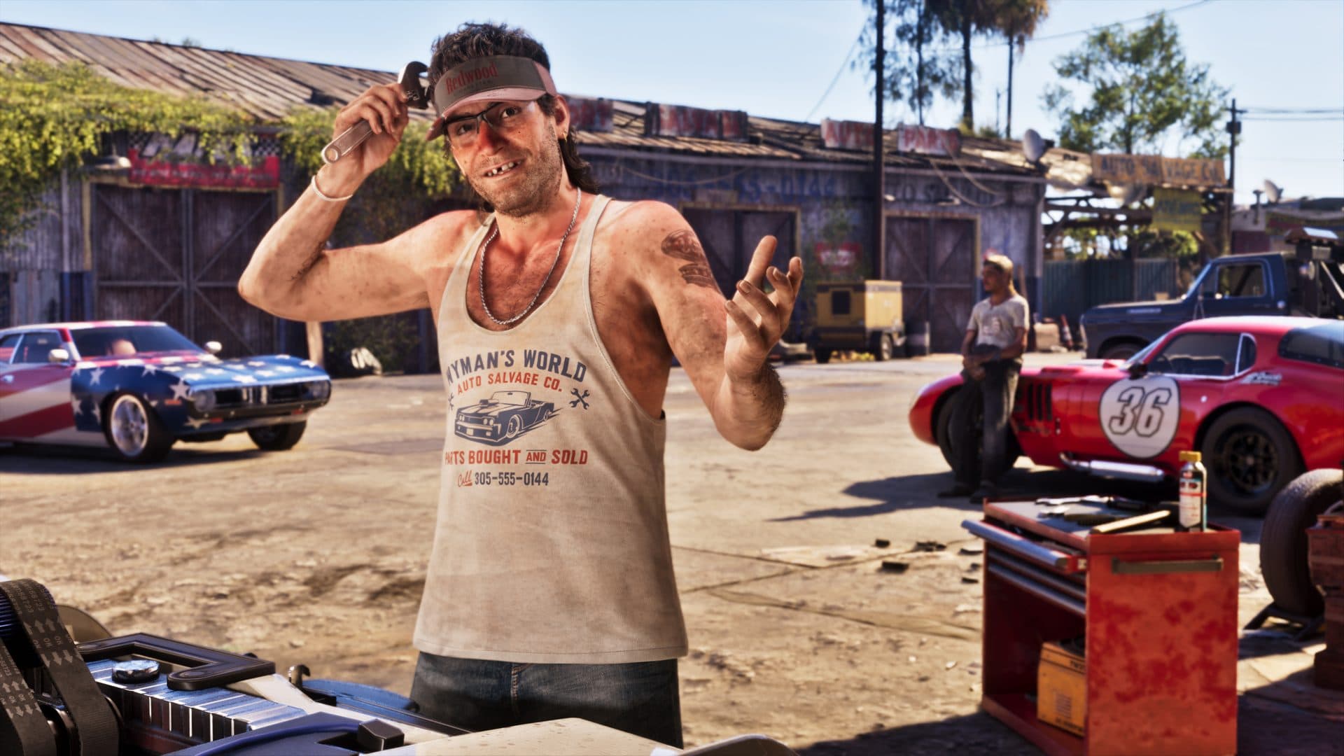 A man in a Wyman's World shirt among a yard of classic cars