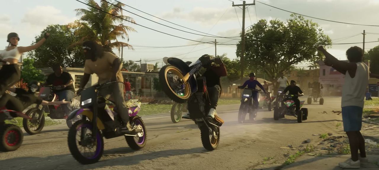 A group of dirt bikes doing wheelies down a residential street in daylight.