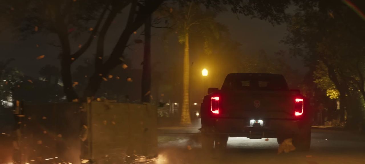 Tail lights of a raised pick-up on an unlit road.